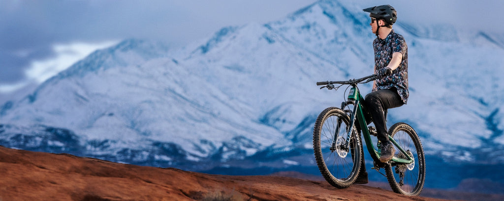 Mountain biker sitting on Guerrilla Gravity full suspension bike with snow capped peaks in the background