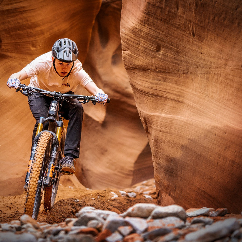 Mountain biker riding a Guerrilla Gravity bike in a red rock slot canyon