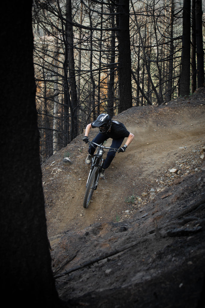 GG Mountain biker riding bern through burnt trees